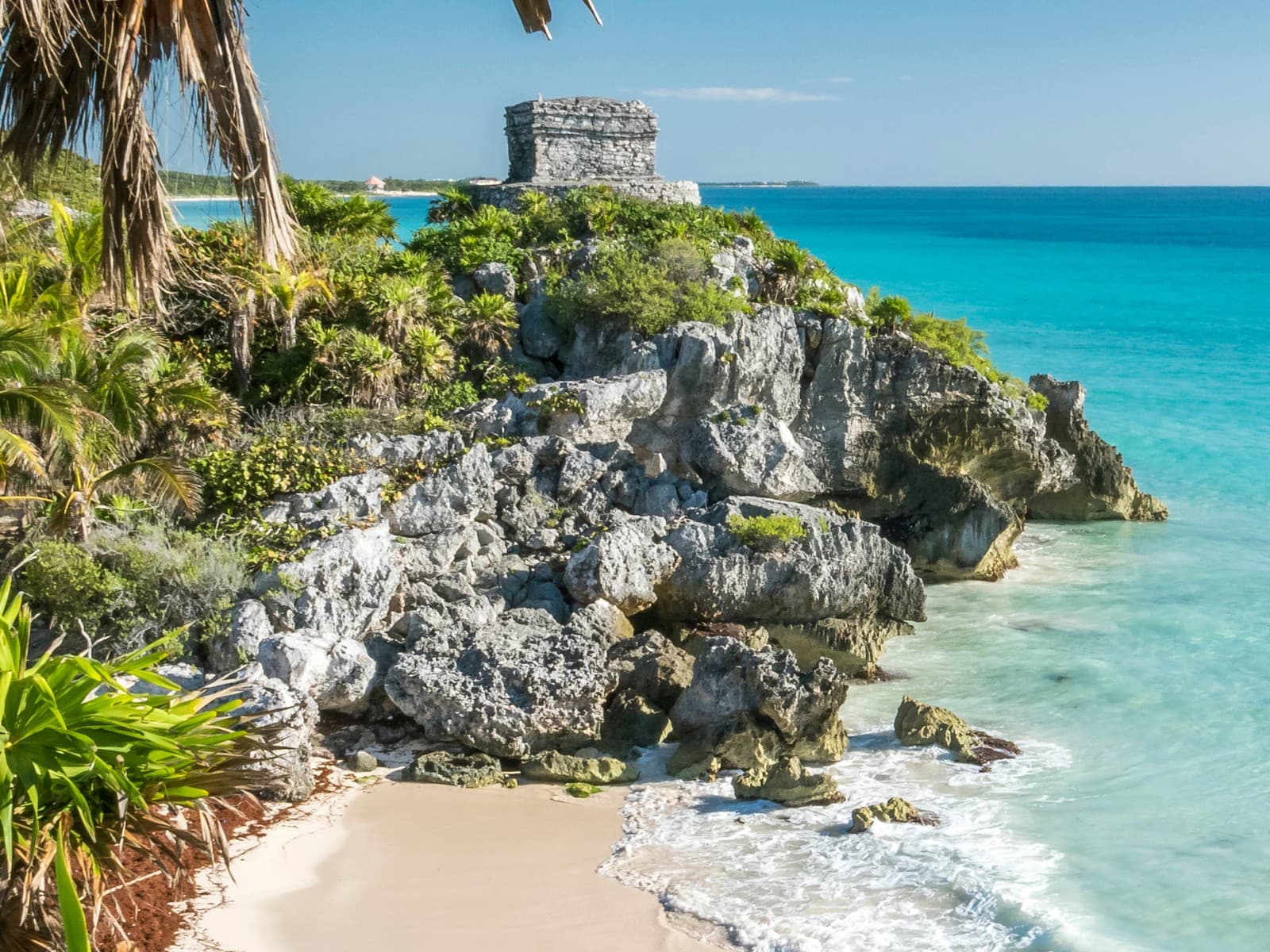 Maya-Tempelruine von Tulum auf einer Felsklippe über dem türkisfarbenen Karibischen Meer, umrahmt von Palmen und einem hellen Sandstrand