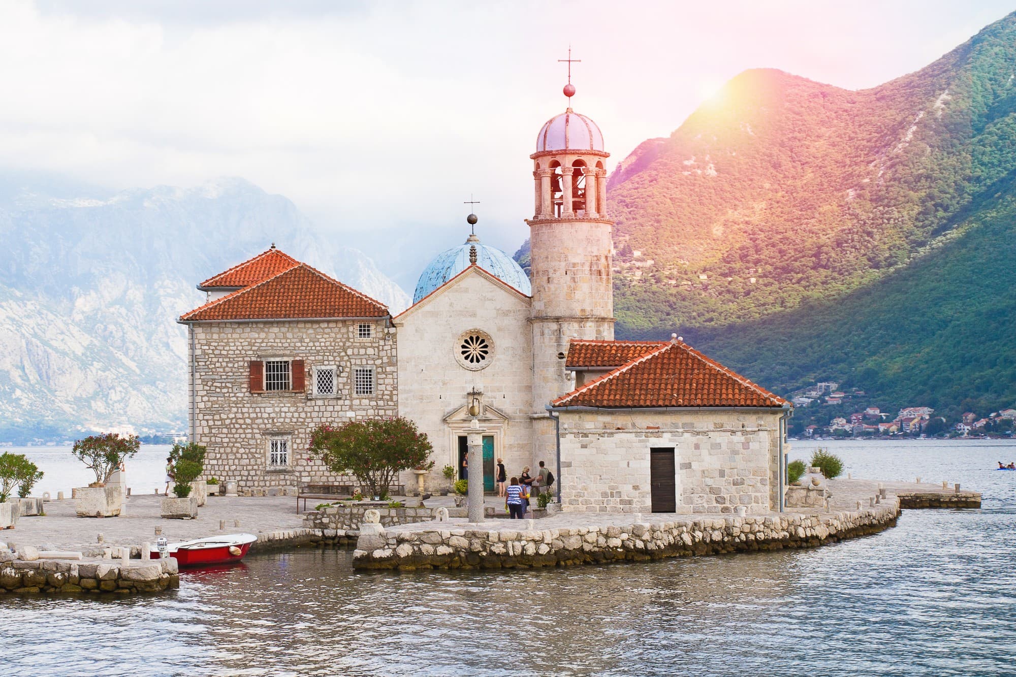 Die Klosterinsel Gospa od Škrpjela (Our Lady of the Rocks) mit Kirche und Glockenturm in der Bucht von Kotor vor Perast, dahinter grüne Berge